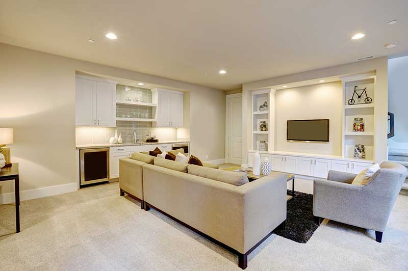 Basement with mounted tv, carpeted floor, wet bar, and stairs to go up to the main floor.