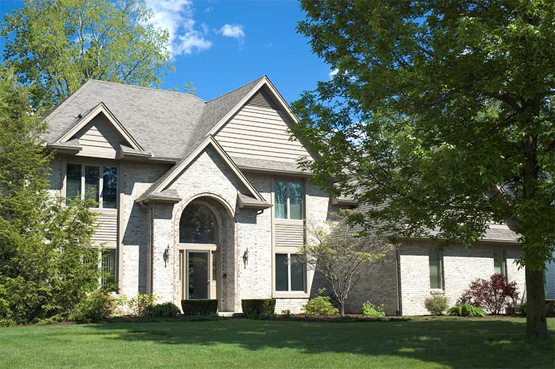 Front of the house with windows, trees, and flowers.