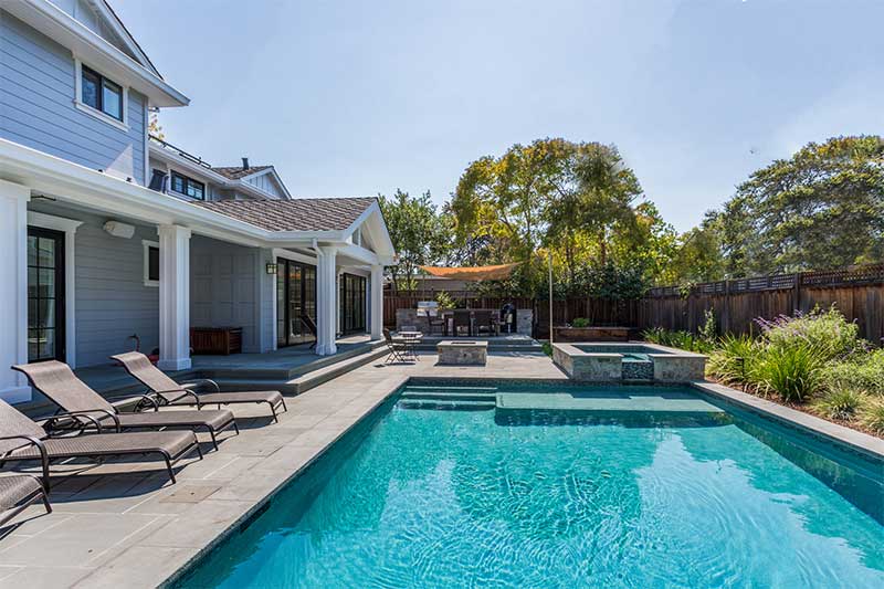 Backyard pool with hot tub and green space.