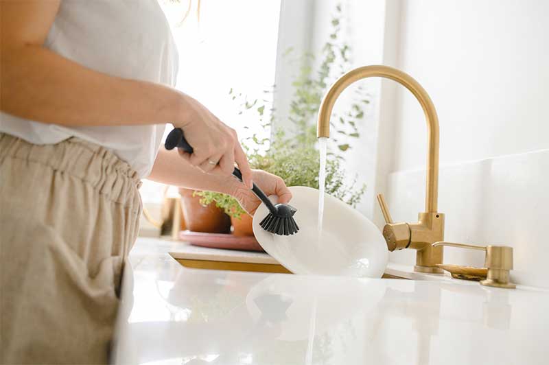 Women washing her dishes with a scrubber.