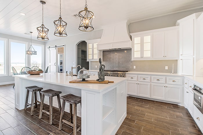 Full kitchen with white cabinets, island and seating.